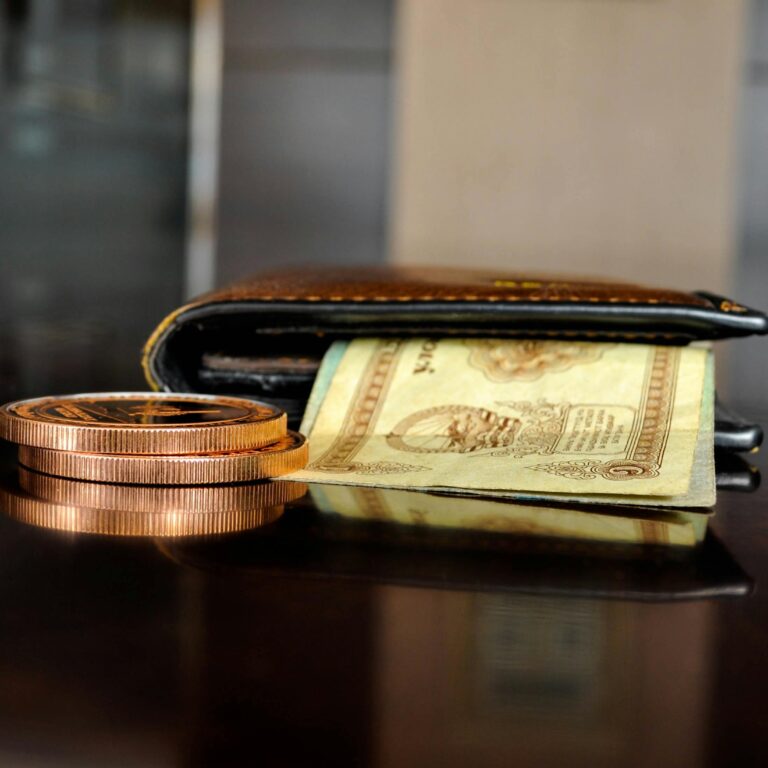 Arrangement of antique coins and banknotes beside a wallet, reflecting luxury finance.