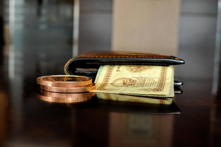 Arrangement of antique coins and banknotes beside a wallet, reflecting luxury finance.