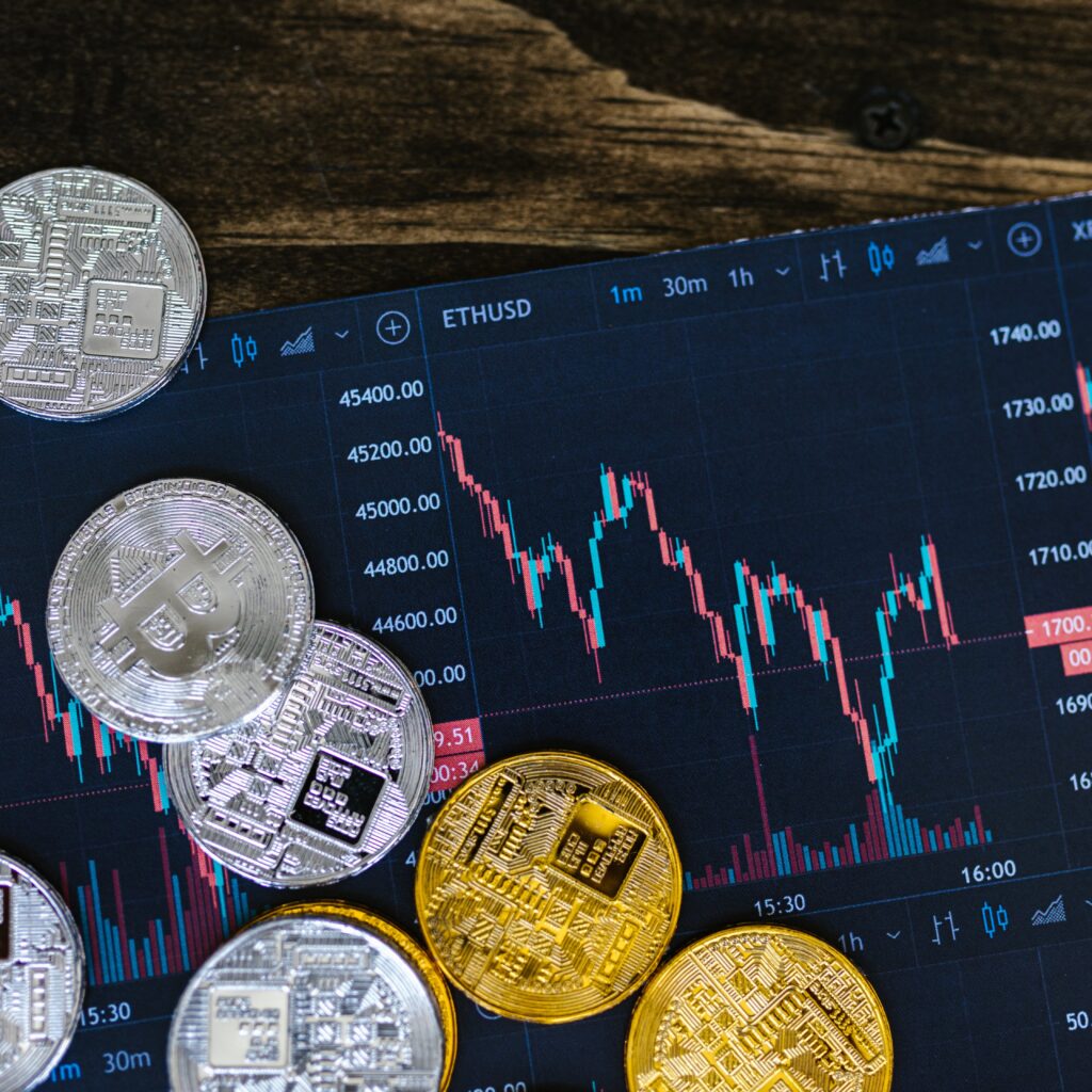 Close-up of gold and silver cryptocurrency coins on a digital trading chart.